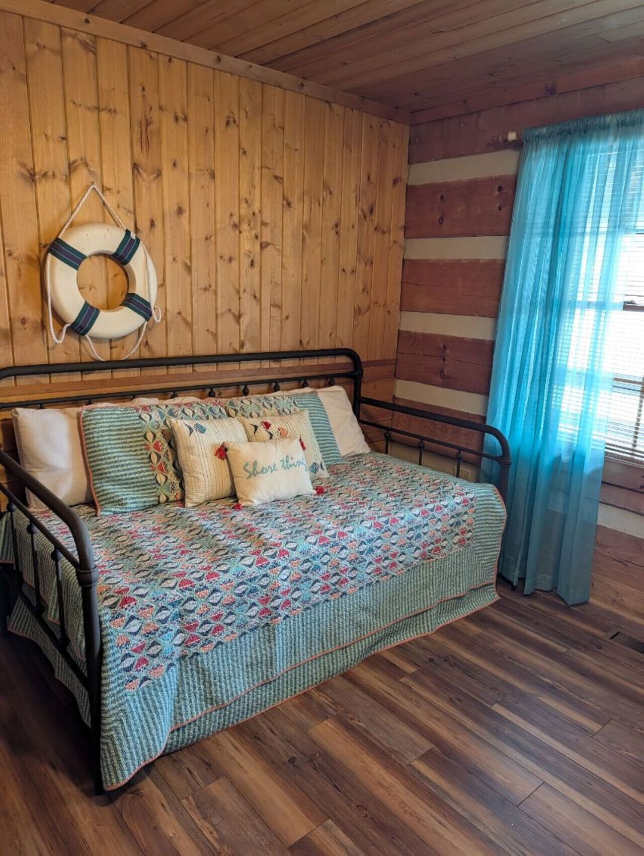 Une chambre dans une cabane en bois, avec un lit, des oreillers et un gilet de sauvetage accroché au mur.