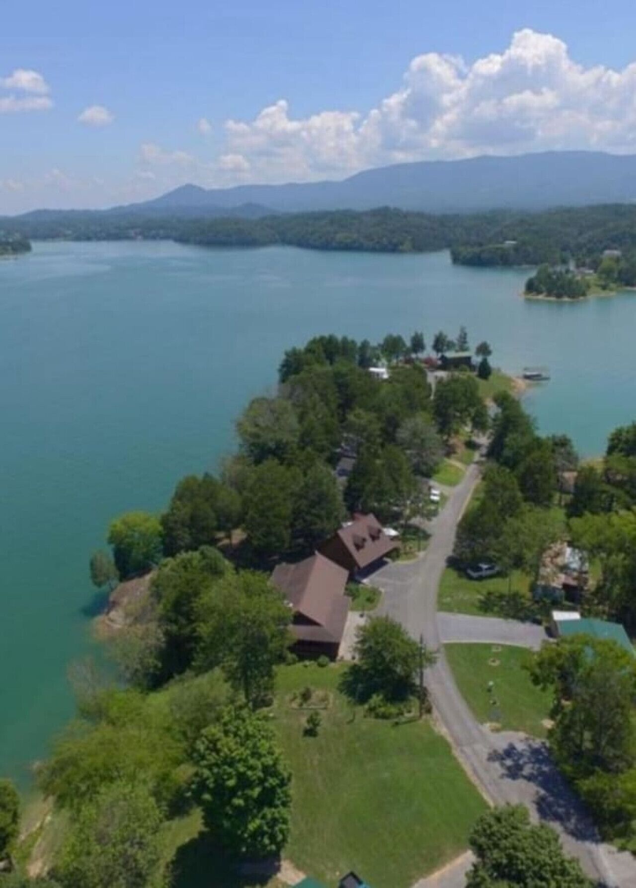 An aerial view of a lakeside property with a main house, a guest house, and a boat dock.