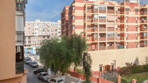 Un edificio residencial de varios pisos con balcones, estacionamiento y un pequeño jardín.