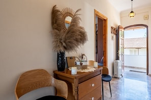 A room with a wooden dresser, a mirror with a feather decoration, a wicker basket, and a suitcase.