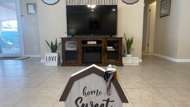 Un saló amb un televisor pla gran, un moble de roba de fusta i un cartell amb la inscripció "home Sweet home".