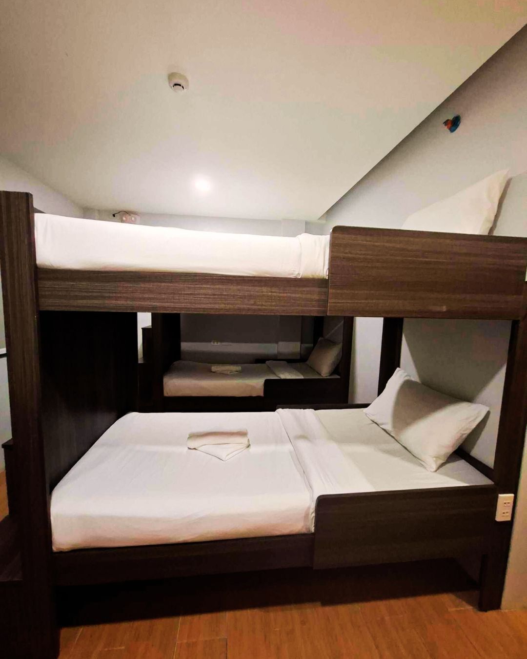 Un letto a castello con una cuccetta inferiore e un letto singolo, entrambi con biancheria bianca.