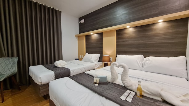 A hotel room with two beds, a desk, and a chair. There are towels and toiletries on the beds. - Rudhil's Place Hotel (Cebu City)