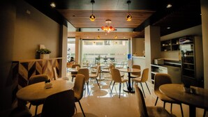 A modern restaurant with round tables and chairs, a wooden ceiling, and pendant lights. - Rudhil's Place Hotel (Cebu City)
