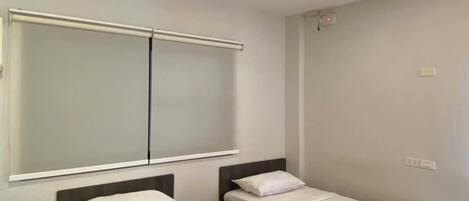 A hotel room with two single beds, a large mirror, and a wooden floor.