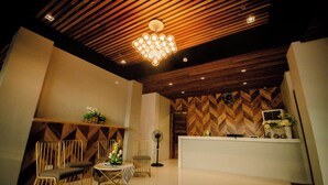 A reception area with a wooden herringbone ceiling, a reception desk, and a seating area with chairs and a table. - Rudhil's Place Hotel (Cebu City)