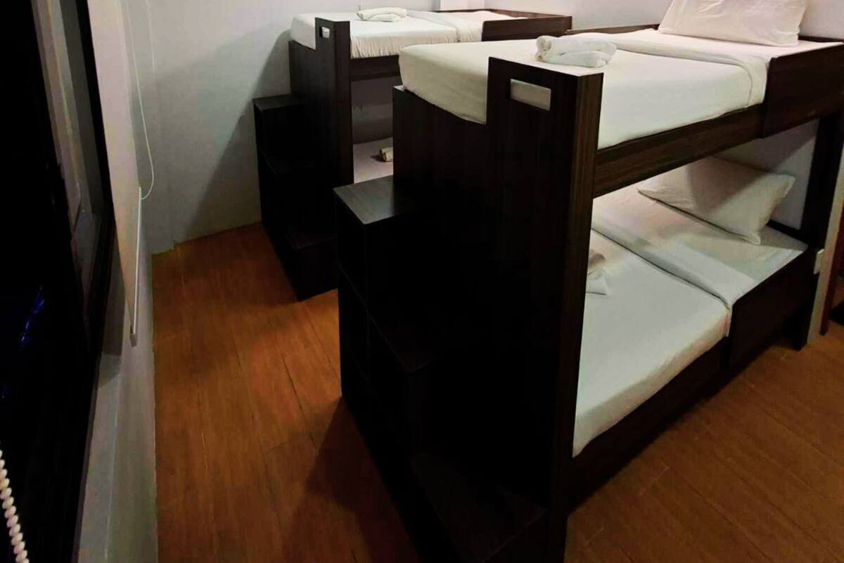 A room with bunk beds, a wooden floor, and a white wall.