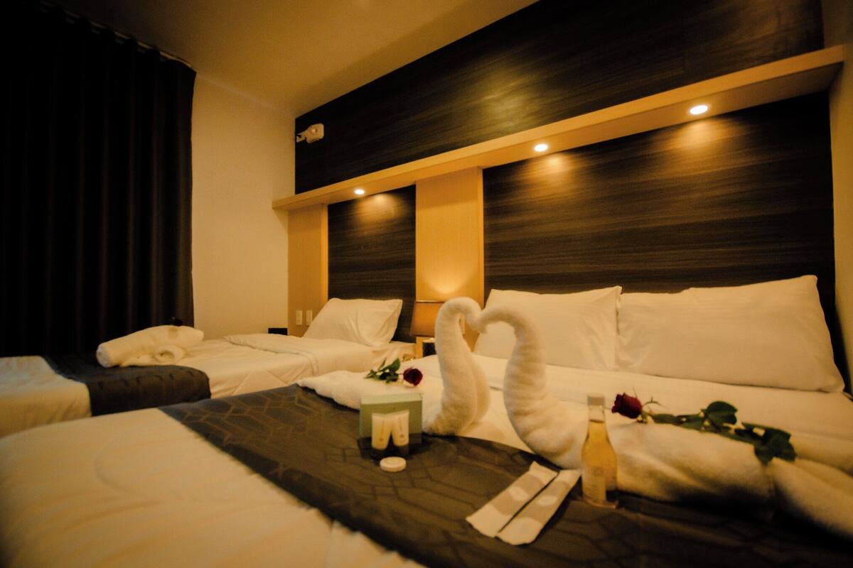 A hotel room with two beds, a wooden headboard, and a nightstand with toiletries.