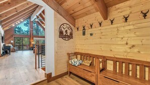 A cozy cabin interior with a wooden bench, a logo on the wall, and a view of the outdoors. - Big Foot’s Den on the 10/Northstar Resort Truckee (Truckee)