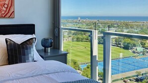 Un dormitorio con un amplio ventanal que da a una vista panorámica de la ciudad y un cuerpo de agua.