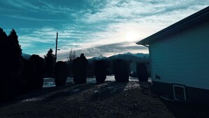 A house with a driveway leading to a mountain view. - The Whispering Cedar (Valemount)