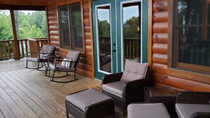 Eine Holzterrasse mit Korbmöbeln und einer Glastür, die zu einem Außenbereich führt.