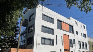 Een modern meerlaags gebouw met een witte gevel, bakstenen accenten en grote ramen.