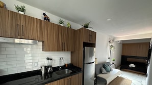 Een moderne keuken met houten kastjes, een zwart aanrechtblad en een inbouwkoelkast.