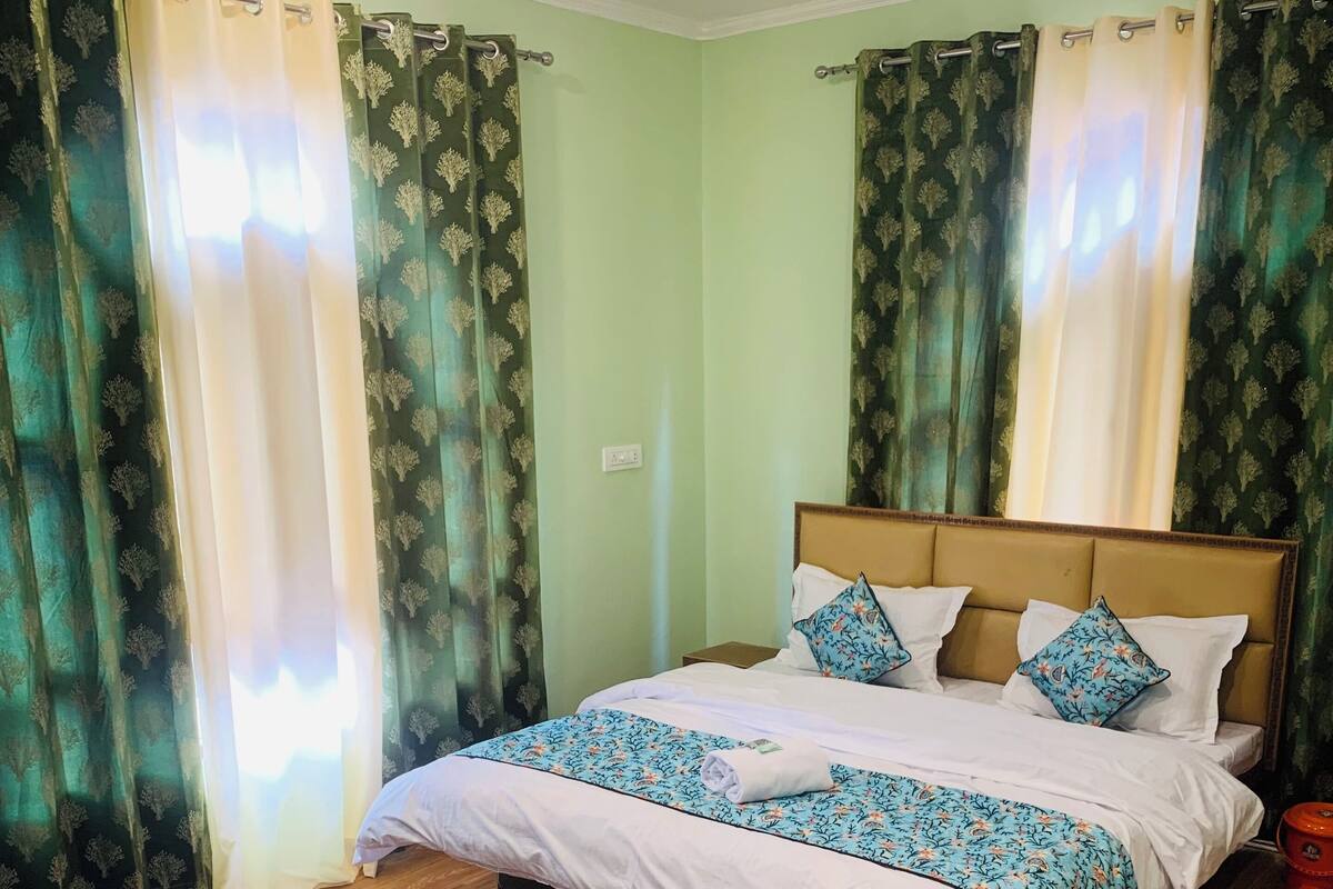 A neatly made bed with a floral bedspread, a wooden headboard, and two pillows.