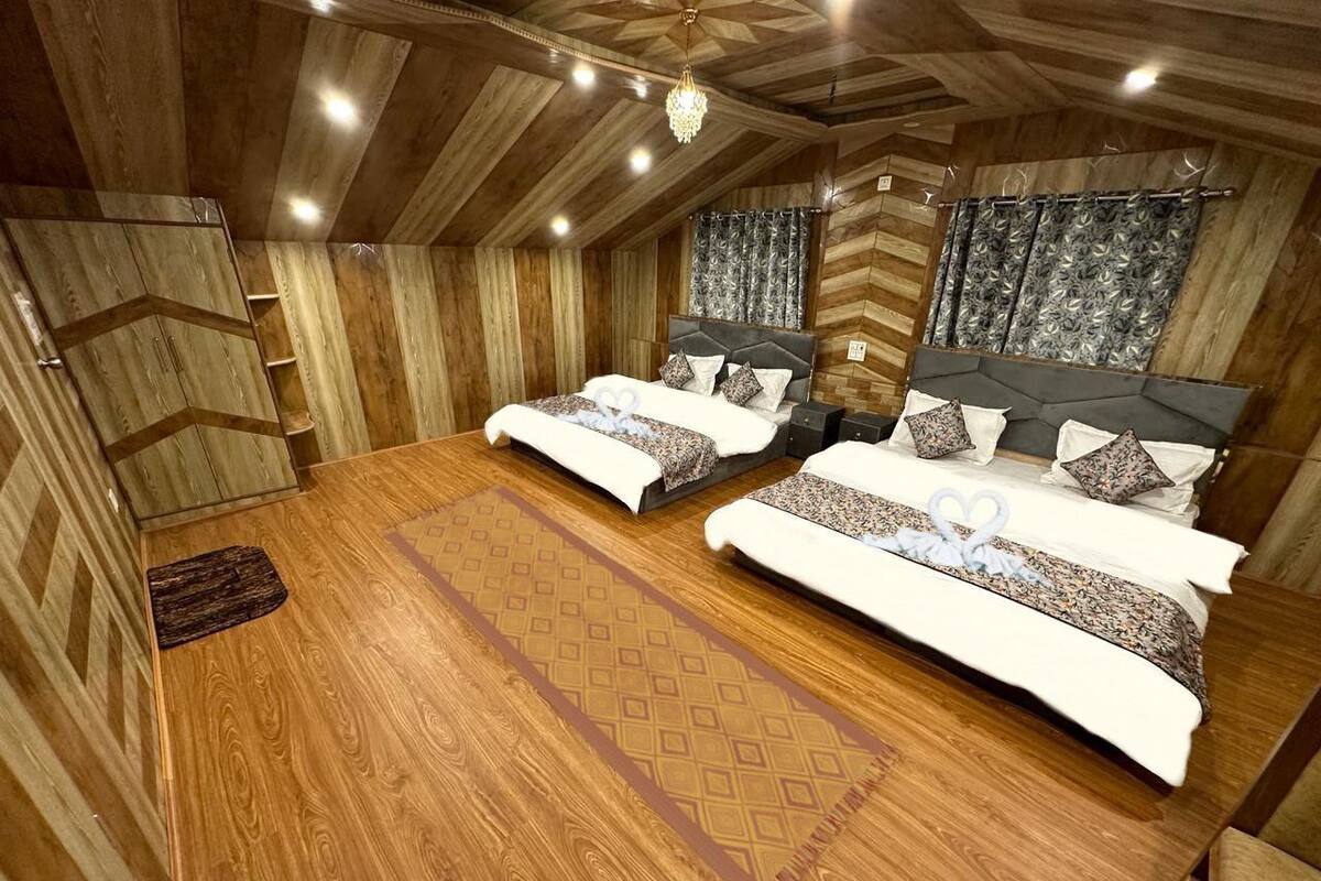 A wooden-themed bedroom with two beds, a large wooden table, and a chandelier.