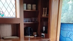 Una cocina compacta con armarios de madera, cafetera, licuadora y un basurero.