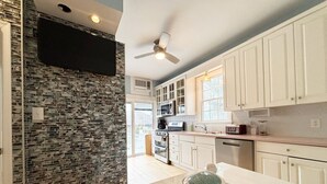 A modern kitchen with white cabinets, a stone backsplash, and a central island with a turtle sculpture. - Hotel-Style Suite, 300’ to Beach (Beach Haven)