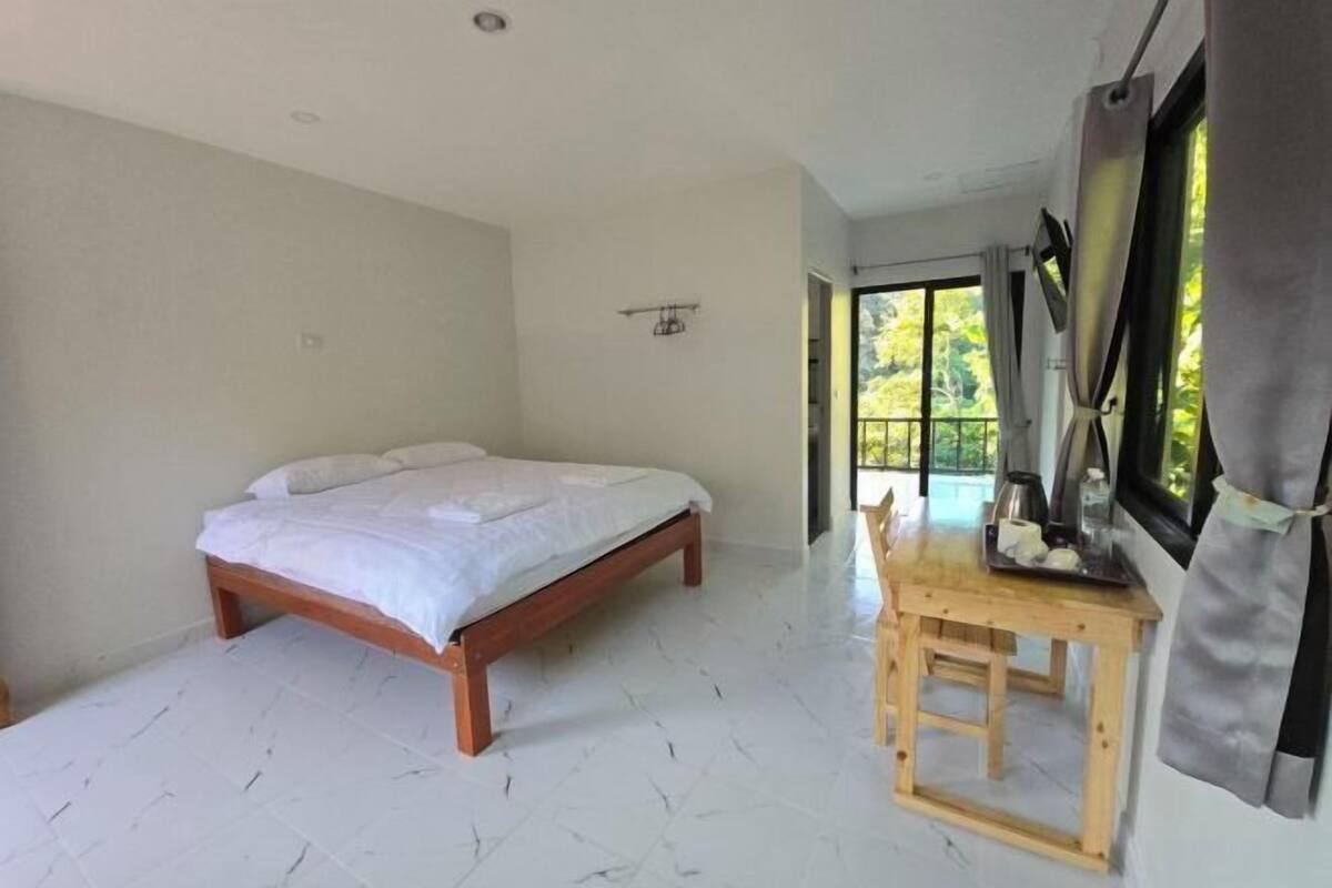 A bedroom with a bed, a wooden table, and a window with curtains.