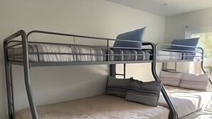 Ein Stockbett mit einer unteren Liege und einer Matratze auf dem Boden.