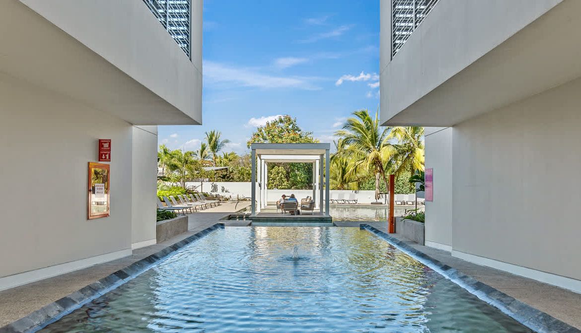 A pool area with a clear view of the sky and palm trees in the background.