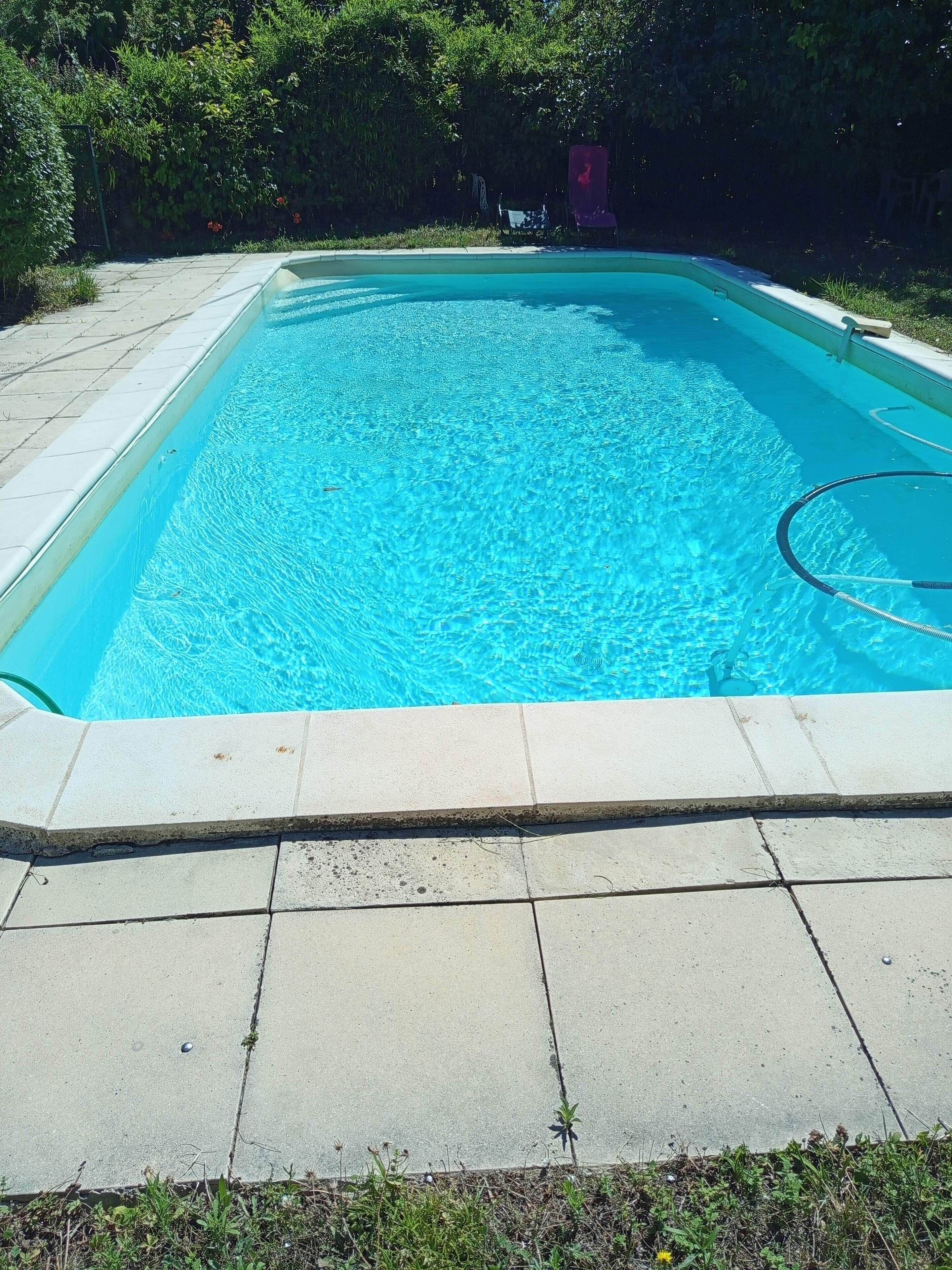 Une piscine rectangulaire à l’eau d’un bleu limpide, entourée d’une terrasse carrelée.