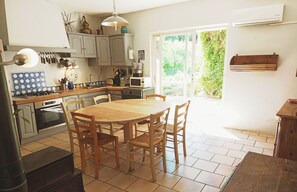 Une cuisine avec une table et des chaises en bois, un poêle et divers ustensiles de cuisine.