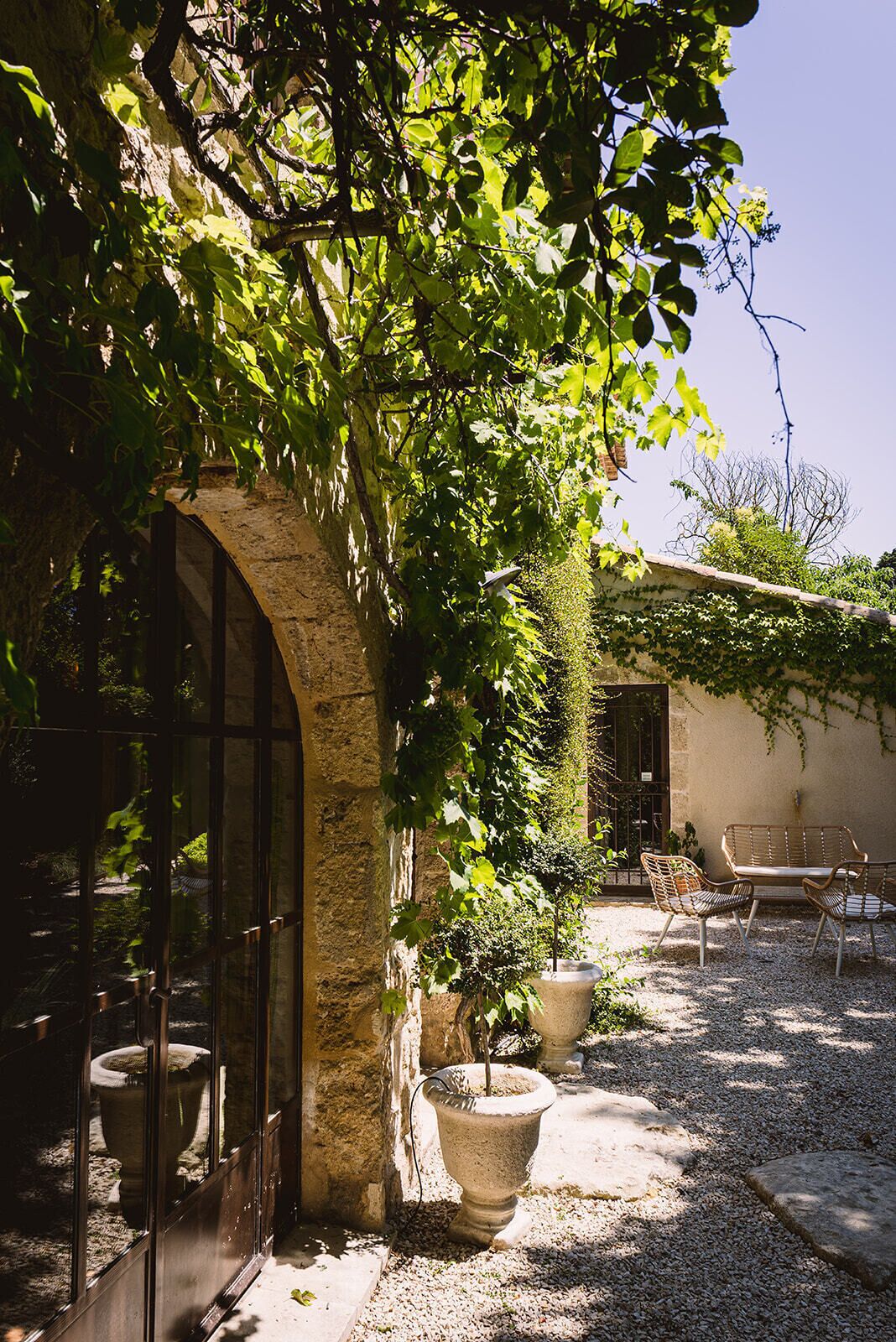 A courtyard with a stone archway, potted plants, and outdoor furniture.