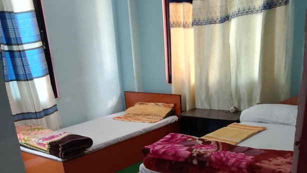 A room with two beds, green carpet, and curtains.