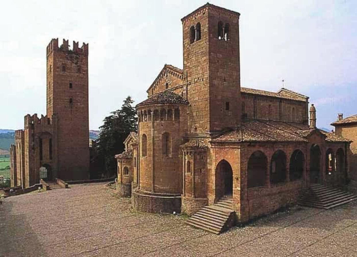 A historic building with a central tower, a smaller tower, and a courtyard.