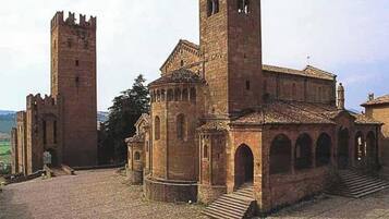 A historic building with a central tower, a smaller tower, and a courtyard.