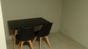 Una habitación pequeña con un escritorio de color oscuro y dos sillas negras.