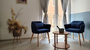 Una stanza con due poltrone blu, un tavolino di legno e un cesto di vimini con piante essiccate.