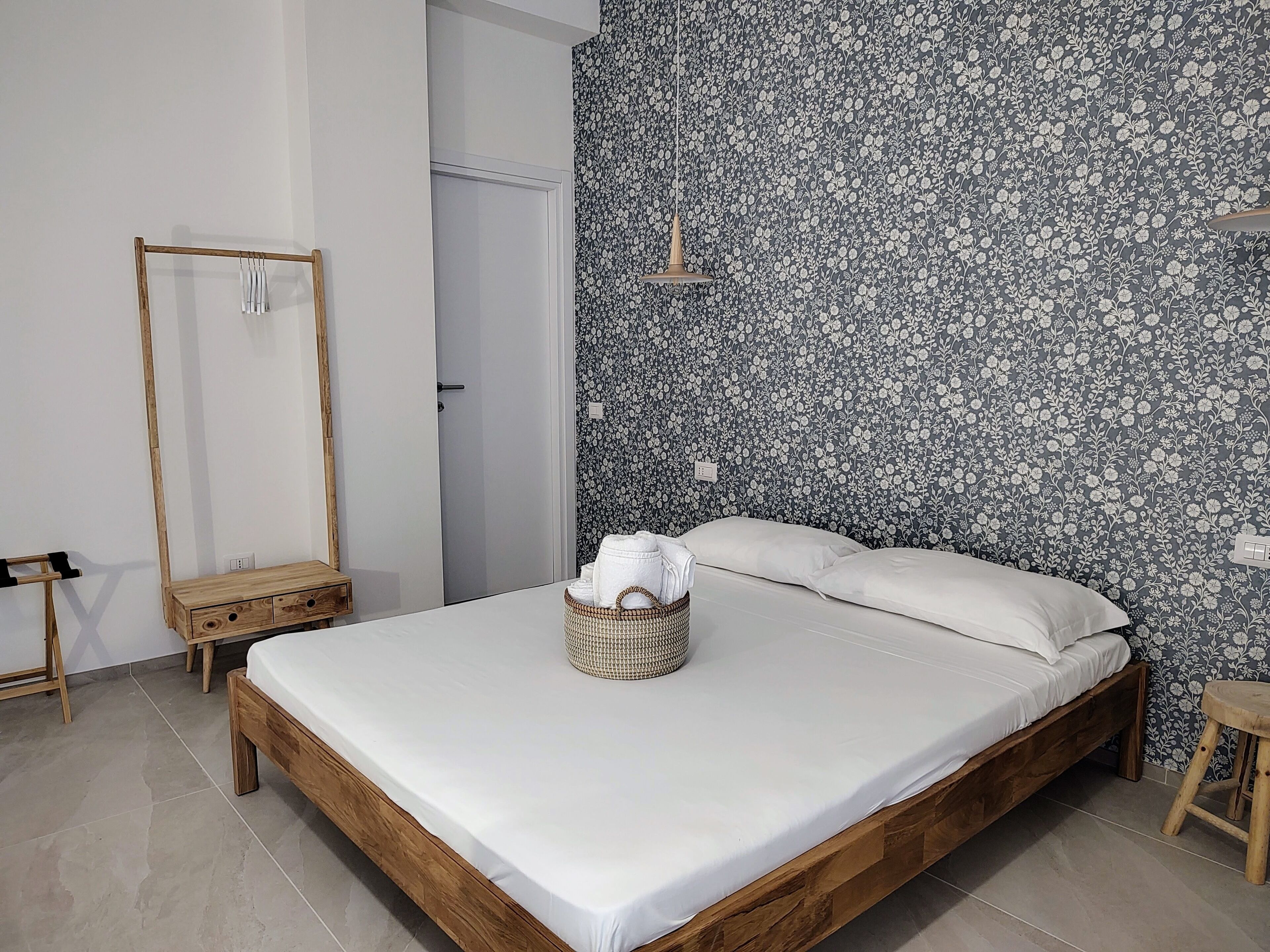 A bedroom with a wooden bed, a mirror, and a floral-patterned wall.