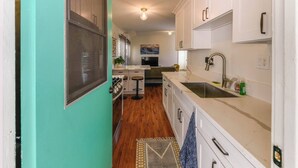 Una cocina estrecha con gabinetes blancos, un lavamanos y una estufa.