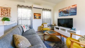 Una sala de estar moderna con un sofá gris, un sillón amarillo y un televisor de pantalla plana.