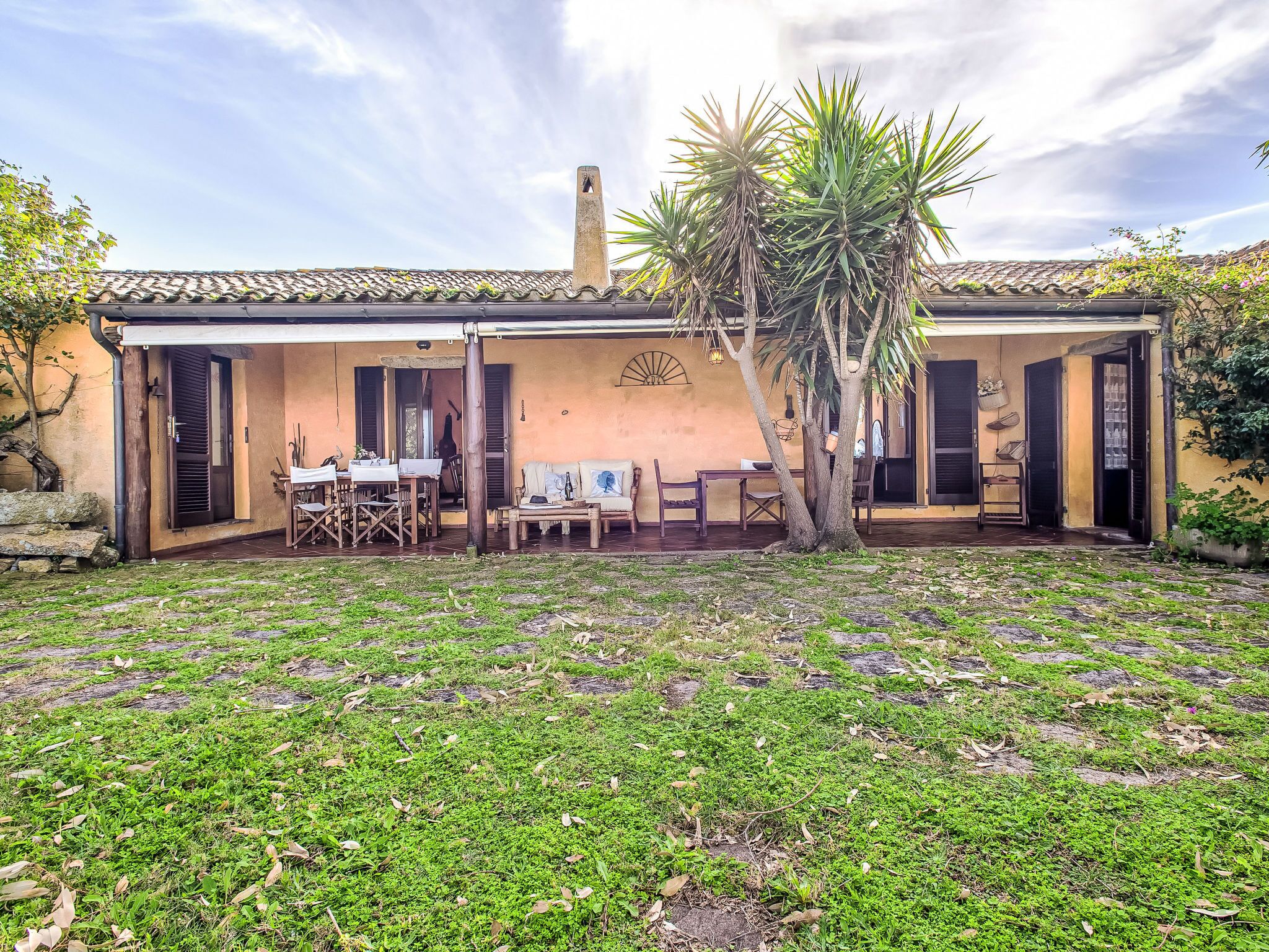 Ein Haus mit Terrasse, Essbereich und überdachter Sitzgelegenheit.