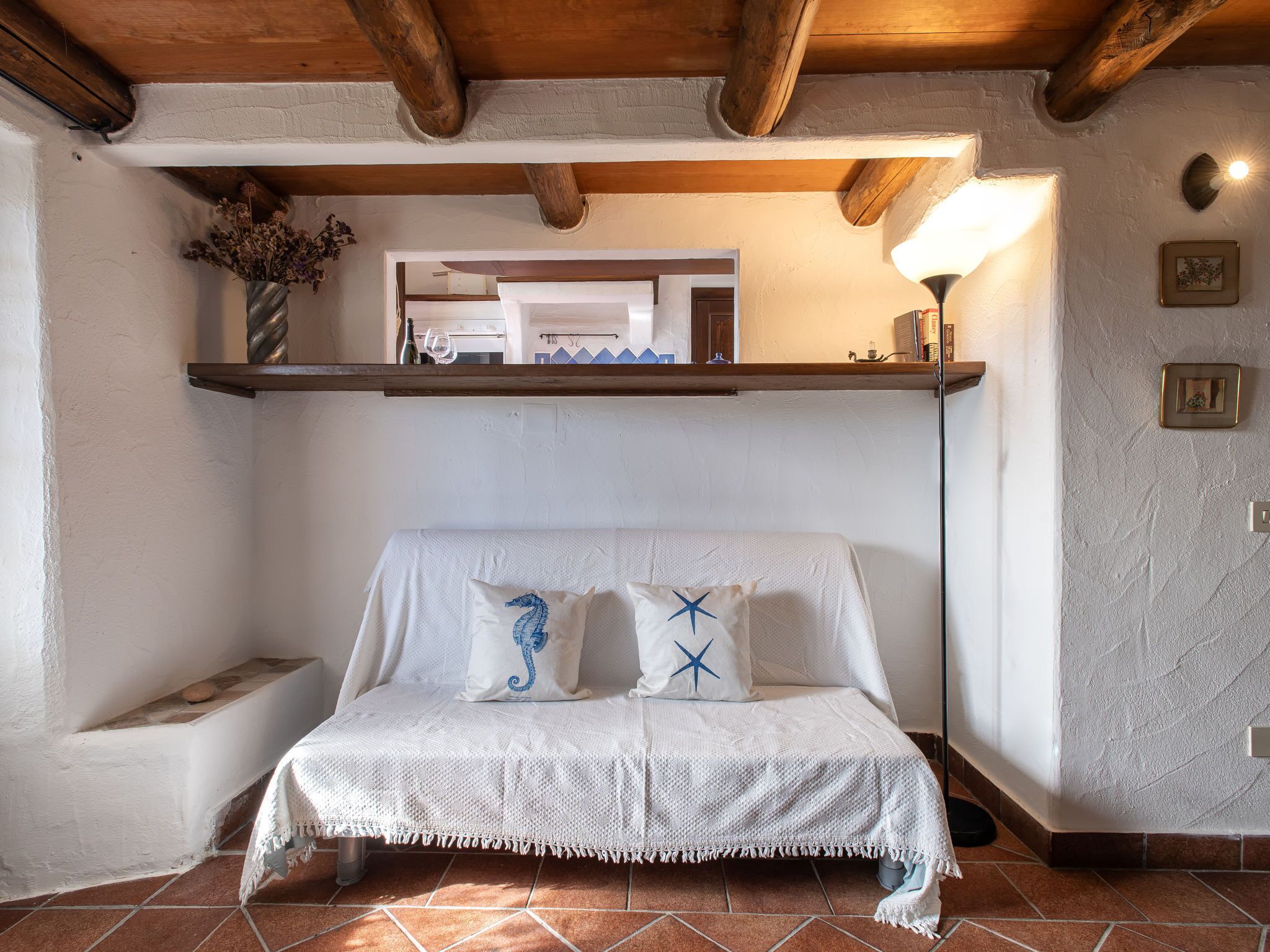 A cozy room with a bed, a shelf with decorative items, and a lamp.