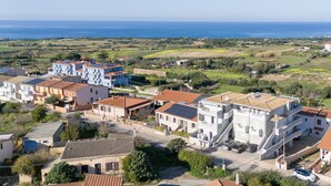 A coastal residential area with modern and traditional buildings, featuring a mix of flat and sloped roofs, and a view of the sea in the background. - Vista Blu by Interhome (Valledoria)