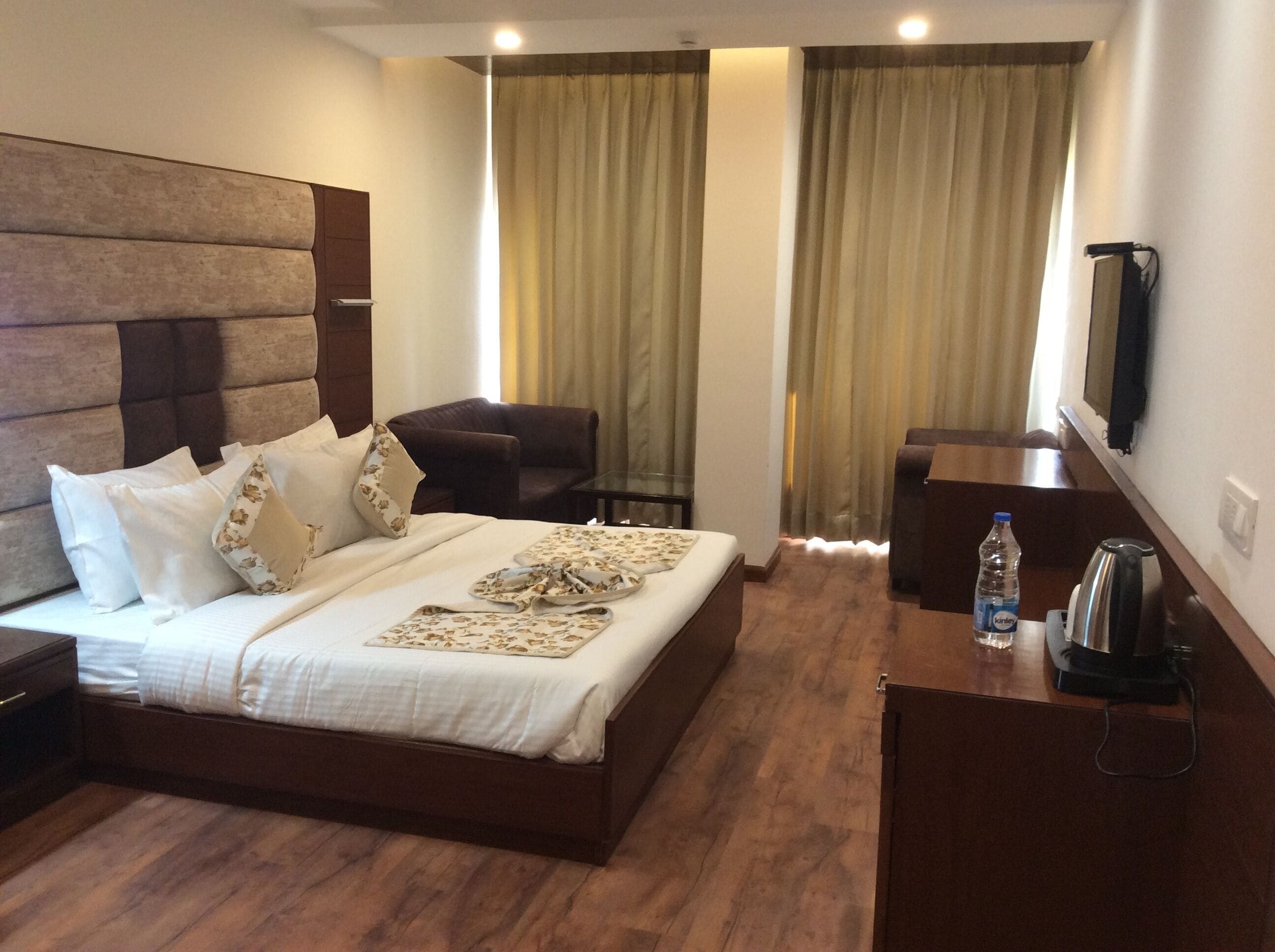 A hotel room with a large bed, a desk, a chair, a television, and a minibar.