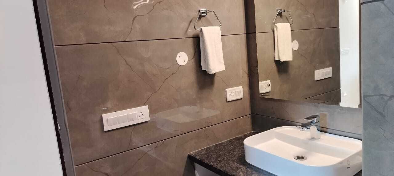 Une salle de bain avec un mur en marbre, un lavabo blanc et un miroir.