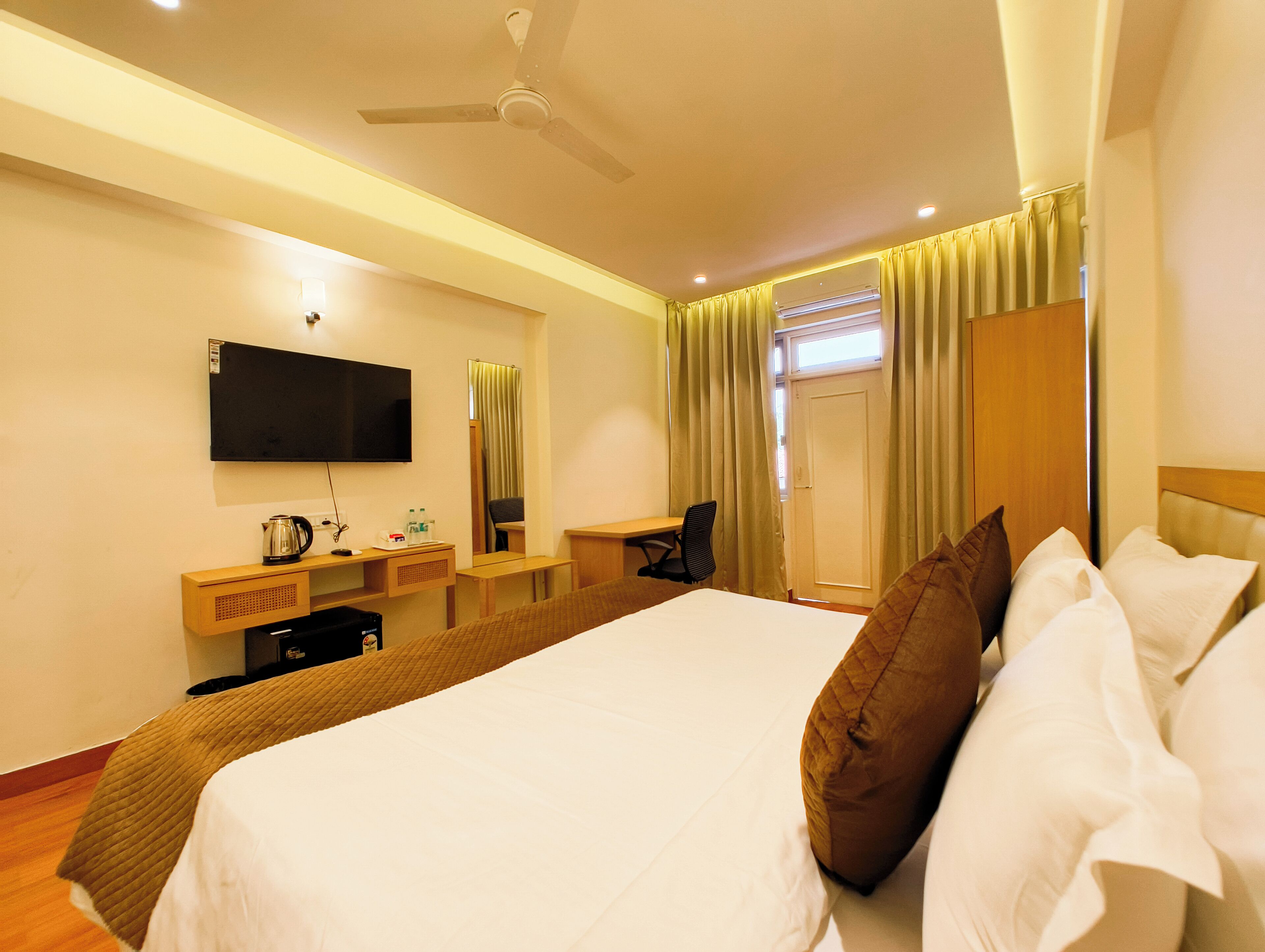 Ein Hotelzimmer mit Bett, Schreibtisch, Stuhl, Fernseher und Kleiderschrank.