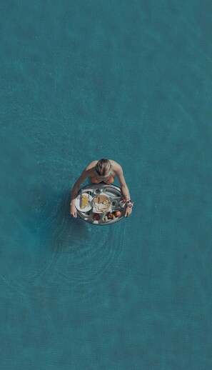 Una persona en una piscina con una bandeja de comida.