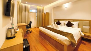 Une chambre d’hôtel équipée d’un lit, d’un bureau, d’une chaise, d’une télévision et d’un ventilateur de plafond.