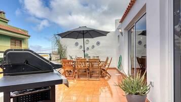 Un patio con una parrilla, mesa de comedor, sillas y una planta en maceta.