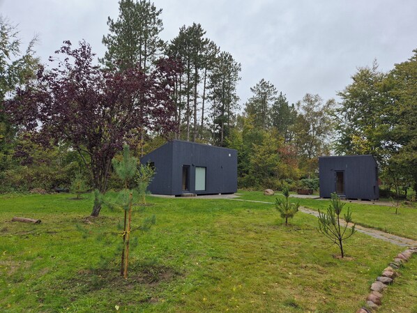 A modern building with a dark exterior, surrounded by a grassy area and trees.
