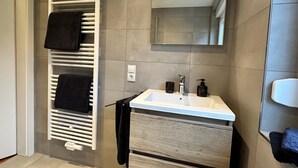 A modern bathroom with a built-in towel rack, a sink with a mirror above it, and a light switch on the wall. - Tante Hedwig - cozy vacation apartment in Rodalben close to the rock hiking trail (Rodalben)