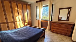 A bedroom with a bed, a dresser, a mirror, and a window with curtains. - Exclusive use cottage all on one floor, fenced garden. Animals welcome (Bianzone)