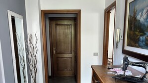 A hallway with a wooden door, a tiled floor, and a wooden dresser with drawers. - Exclusive use cottage all on one floor, fenced garden. Animals welcome (Bianzone)