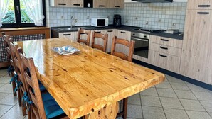 A modern kitchen with wooden cabinets, a large wooden dining table, and a built-in microwave. - Exclusive use cottage all on one floor, fenced garden. Animals welcome (Bianzone)